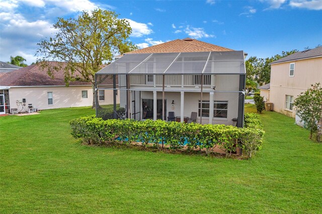 back of property featuring a balcony and a lawn