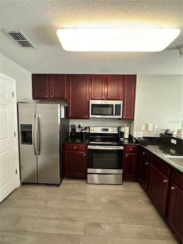 kitchen featuring light hardwood / wood-style flooring, a textured ceiling, and appliances with stainless steel finishes