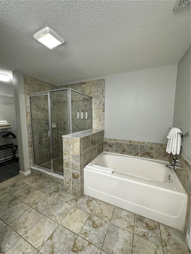 bathroom featuring shower with separate bathtub and a textured ceiling