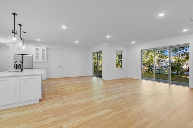 unfurnished living room featuring sink and light hardwood / wood-style floors