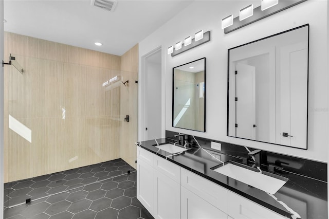 bathroom with tile patterned floors, vanity, and a tile shower