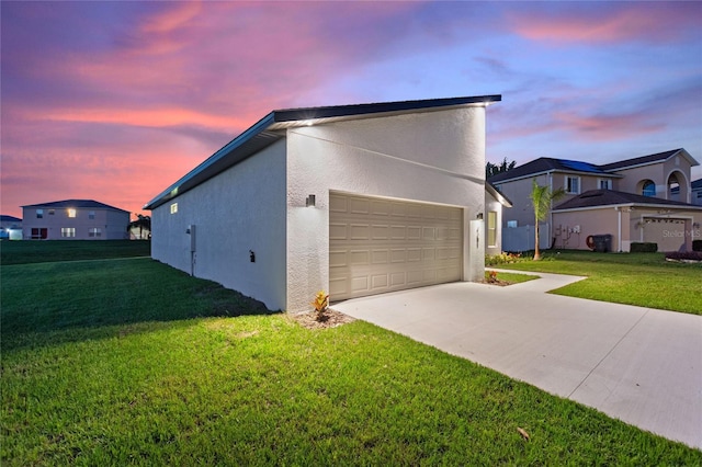1877 Snapper Dr, Kissimmee, FL 34759 - property exterior at dusk featuring a yard, a garage, stucco siding, and driveway
