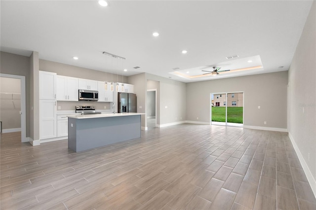 kitchen featuring stainless steel appliances, light hardwood / wood-style floors, hanging light fixtures, an island with sink, and ceiling fan