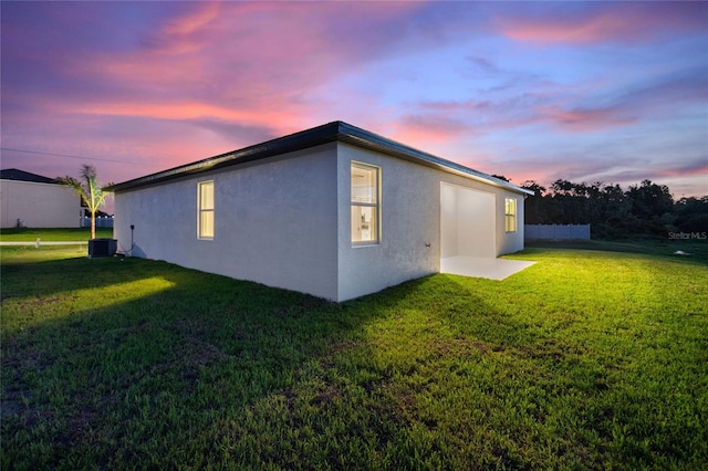 property exterior at dusk with a lawn and central AC