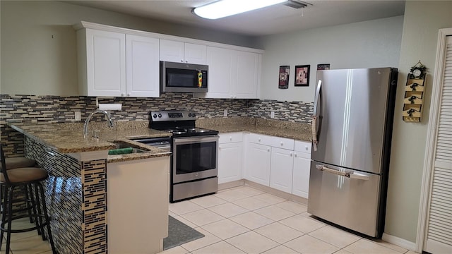 kitchen with dark stone counters, kitchen peninsula, white cabinets, and stainless steel appliances