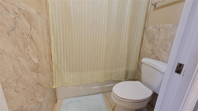 bathroom featuring toilet, tile walls, and shower / bath combo with shower curtain