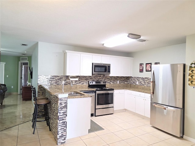 kitchen featuring kitchen peninsula, sink, backsplash, appliances with stainless steel finishes, and white cabinets