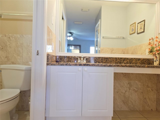 bathroom with toilet, tile patterned floors, tile walls, and vanity