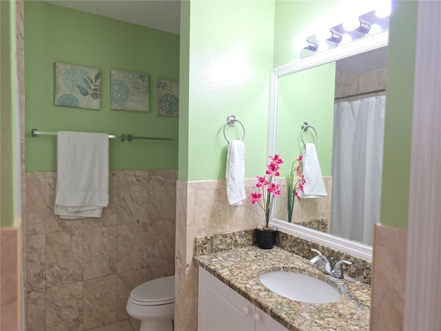 bathroom featuring tile walls, vanity, and toilet