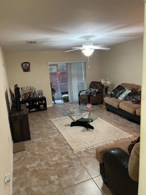 living room featuring ceiling fan and a textured ceiling