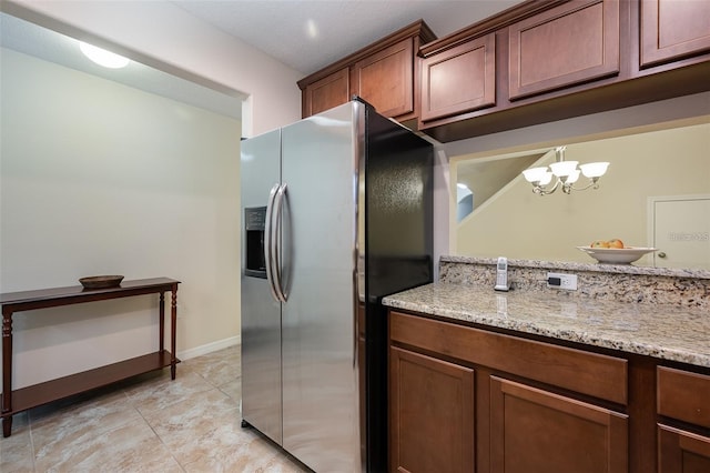 kitchen with stainless steel refrigerator with ice dispenser, light stone counters, light tile patterned floors, a notable chandelier, and pendant lighting