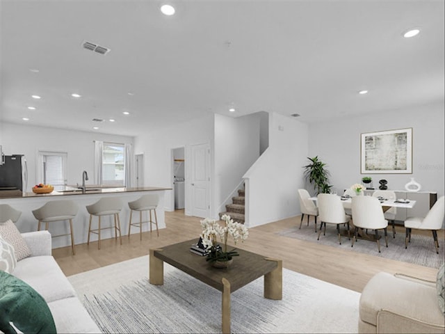 living room with light hardwood / wood-style flooring and sink