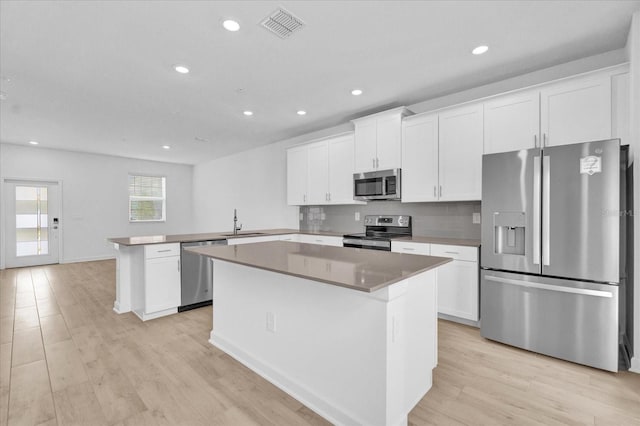 kitchen featuring kitchen peninsula, light hardwood / wood-style flooring, a kitchen island, and stainless steel appliances