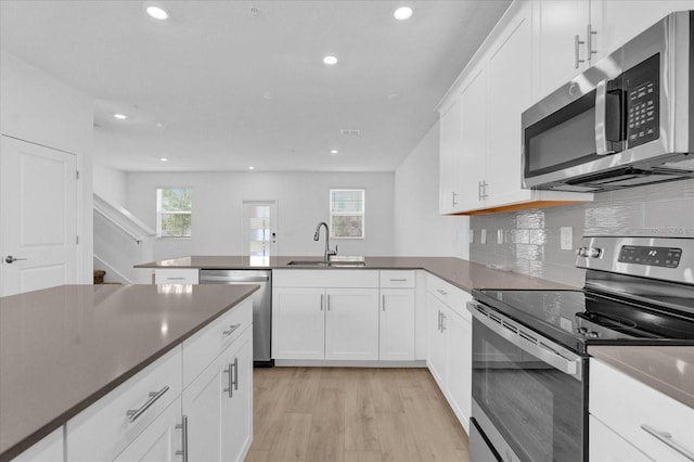 kitchen featuring appliances with stainless steel finishes, light hardwood / wood-style floors, white cabinetry, and sink