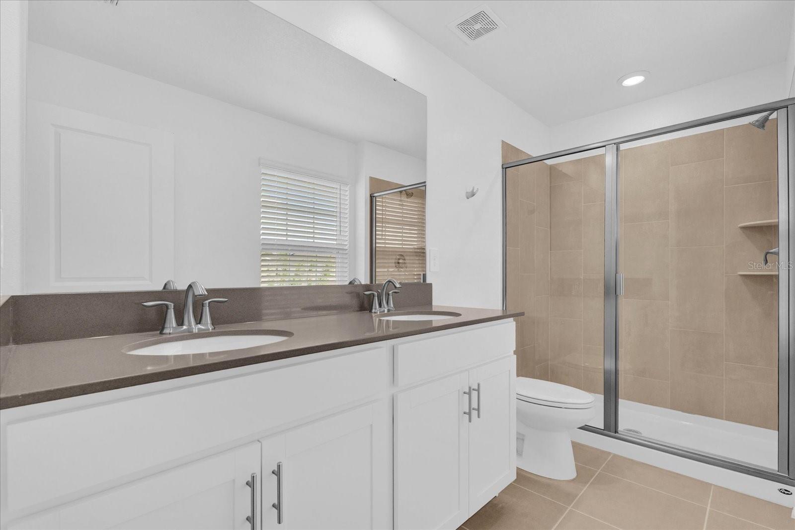 bathroom featuring tile patterned floors, vanity, toilet, and walk in shower