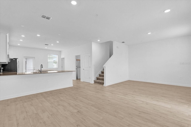 unfurnished living room with light hardwood / wood-style floors and sink