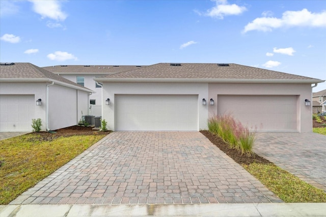 single story home with central air condition unit and a garage