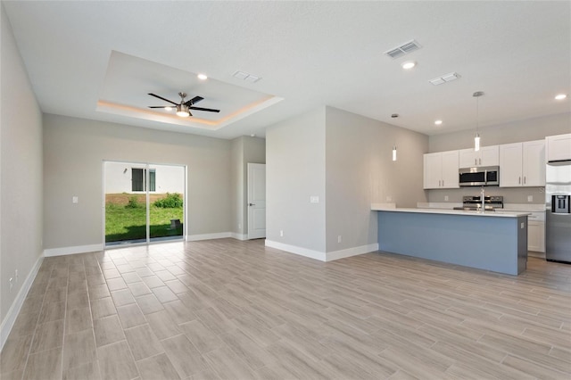 kitchen featuring stainless steel appliances, hanging light fixtures, white cabinets, and light hardwood / wood-style flooring