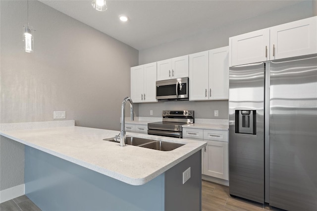 kitchen with white cabinetry, appliances with stainless steel finishes, sink, hardwood / wood-style flooring, and kitchen peninsula