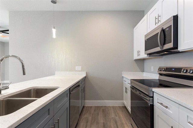 kitchen featuring white cabinets, hanging light fixtures, sink, light stone countertops, and appliances with stainless steel finishes