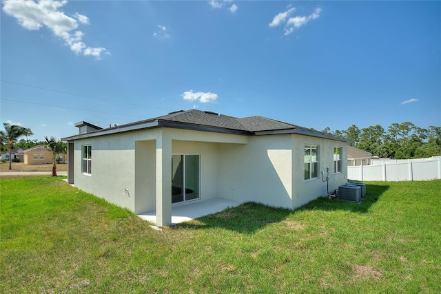 rear view of property with central AC unit, a lawn, and a patio area