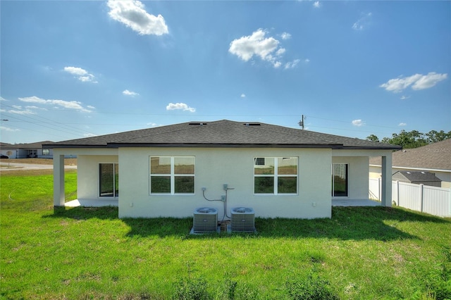 rear view of house featuring central air condition unit and a lawn