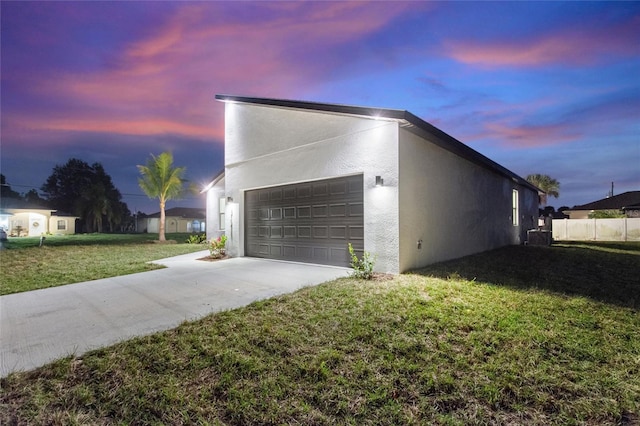 garage at dusk featuring a yard