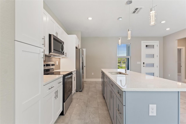 kitchen featuring stainless steel appliances, sink, hanging light fixtures, a kitchen island with sink, and white cabinets