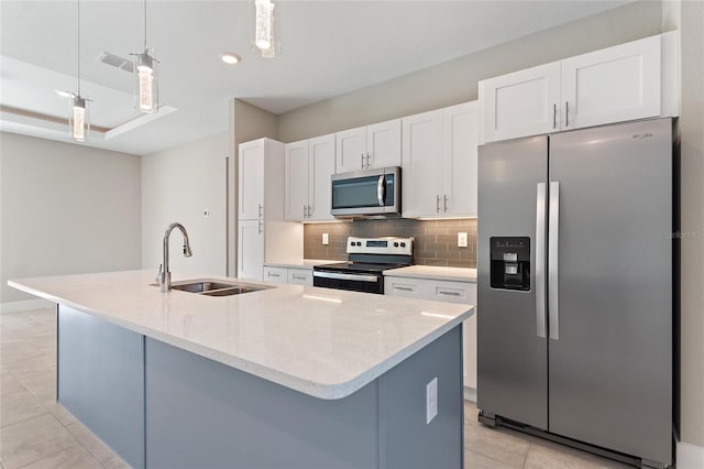 kitchen featuring a center island with sink, sink, white cabinetry, appliances with stainless steel finishes, and hanging light fixtures