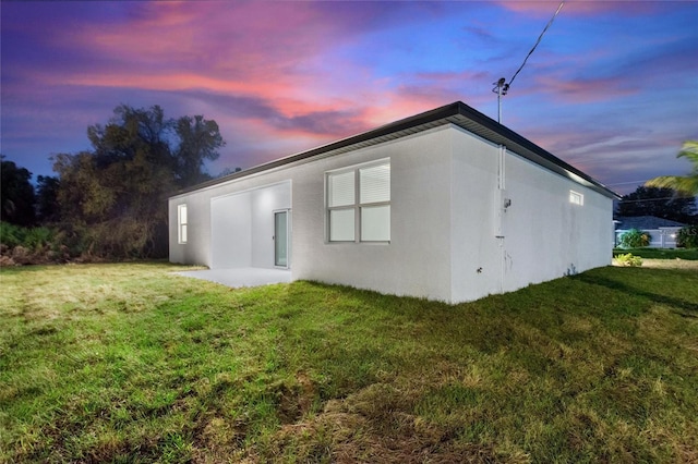 property exterior at dusk featuring a lawn