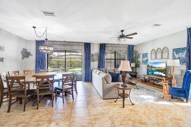 tiled dining room with ceiling fan with notable chandelier and a healthy amount of sunlight