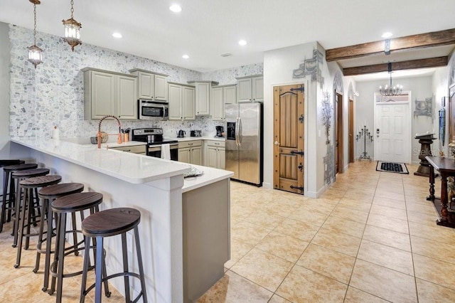 kitchen featuring gray cabinets, hanging light fixtures, appliances with stainless steel finishes, and a kitchen breakfast bar