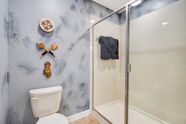 bathroom with toilet, a shower with shower door, and tile patterned flooring