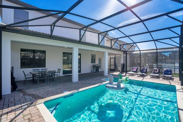 view of swimming pool with glass enclosure, a patio area, and grilling area