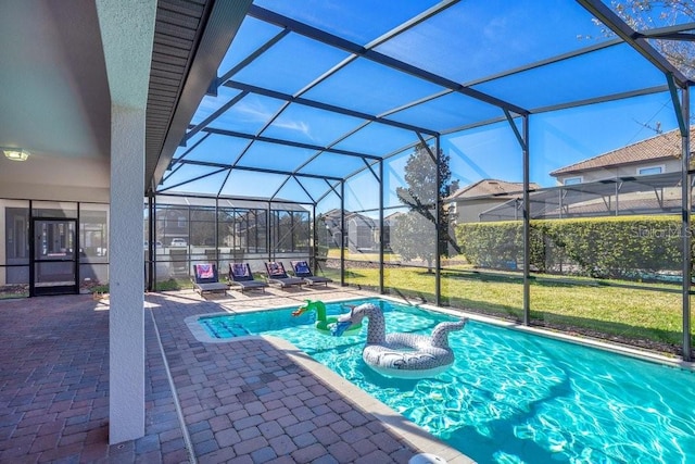 view of pool featuring glass enclosure, a yard, and a patio