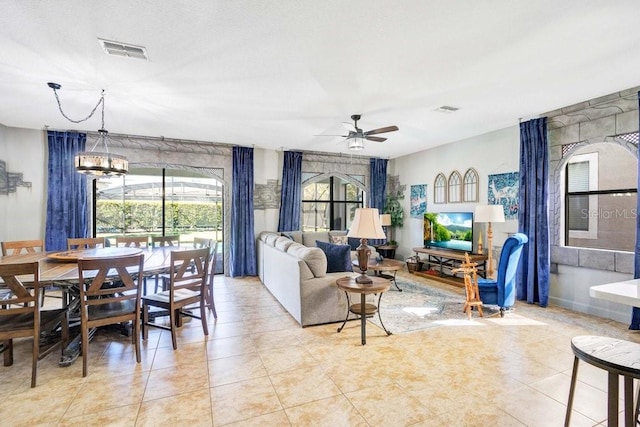 tiled living room with a healthy amount of sunlight and ceiling fan with notable chandelier