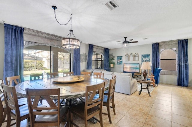 tiled dining area with ceiling fan with notable chandelier