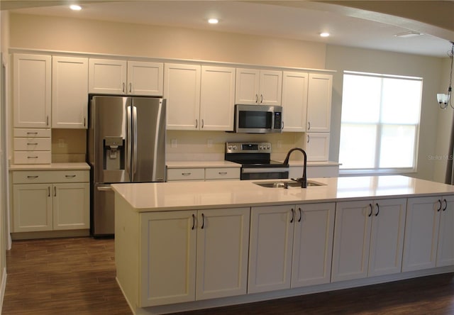 kitchen featuring sink, dark wood-type flooring, appliances with stainless steel finishes, a kitchen island with sink, and white cabinetry