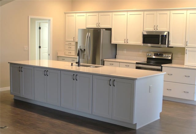 kitchen featuring dark hardwood / wood-style floors, sink, white cabinets, a kitchen island with sink, and stainless steel appliances