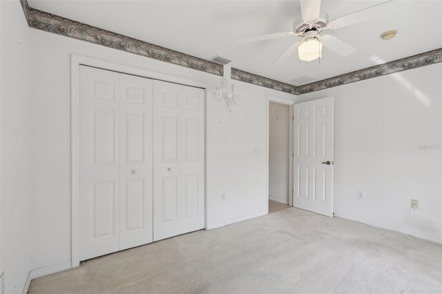 unfurnished bedroom featuring ceiling fan, a closet, and light colored carpet