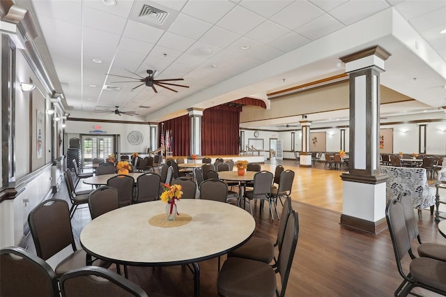 dining space with a paneled ceiling, dark hardwood / wood-style floors, ceiling fan, and decorative columns