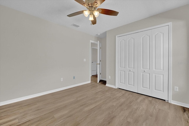 unfurnished bedroom with ceiling fan, light hardwood / wood-style flooring, a closet, and a textured ceiling