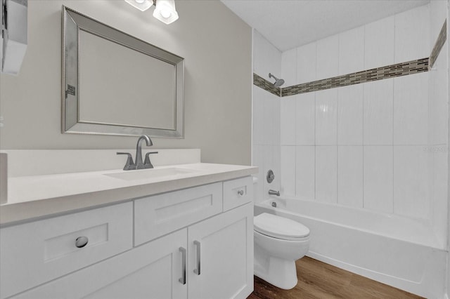 full bathroom featuring wood-type flooring, toilet, tiled shower / bath combo, and vanity