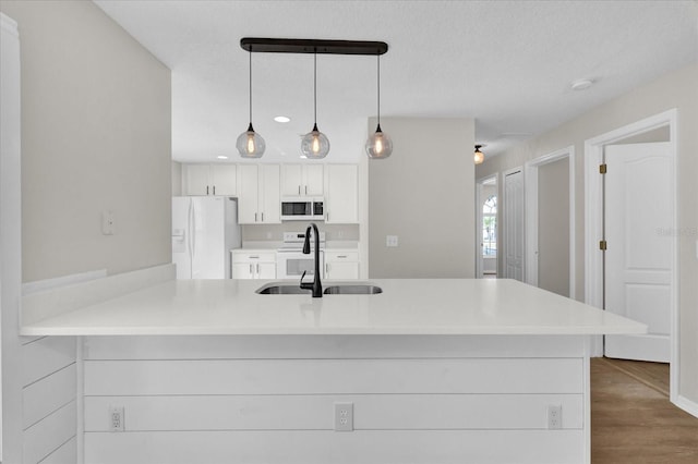 kitchen with pendant lighting, white cabinetry, sink, kitchen peninsula, and white appliances