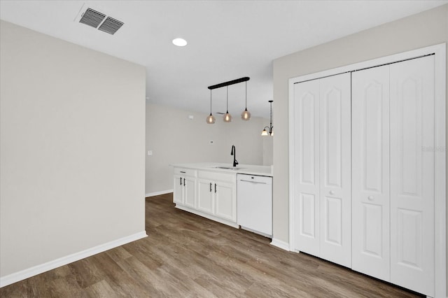 bar with pendant lighting, sink, white cabinets, white dishwasher, and light wood-type flooring