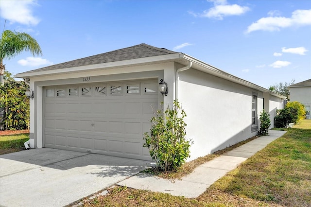 view of side of property with stucco siding, an attached garage, roof with shingles, and driveway