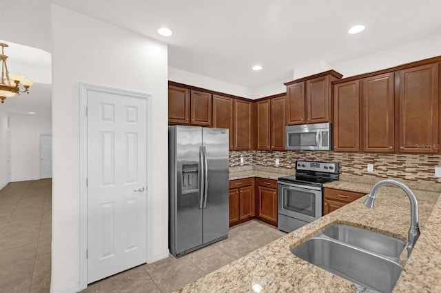 kitchen with tasteful backsplash, sink, stainless steel appliances, light stone counters, and light tile patterned floors