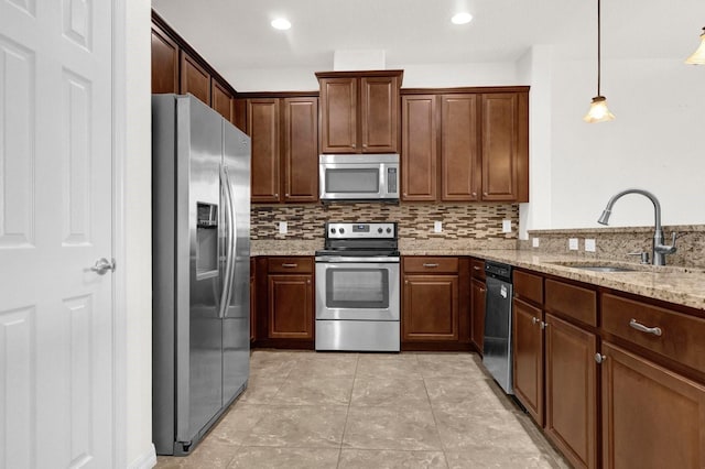 kitchen featuring decorative backsplash, sink, decorative light fixtures, appliances with stainless steel finishes, and light stone counters