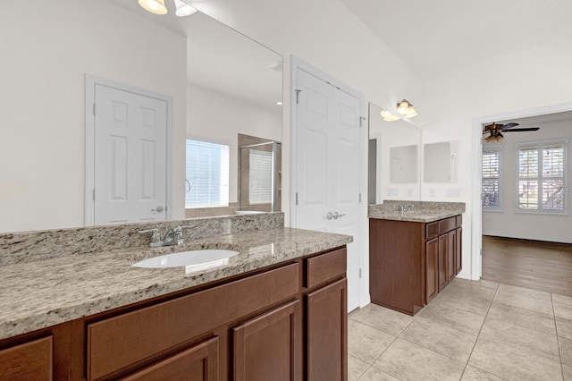 bathroom with vanity, a shower with door, ceiling fan, and a wealth of natural light