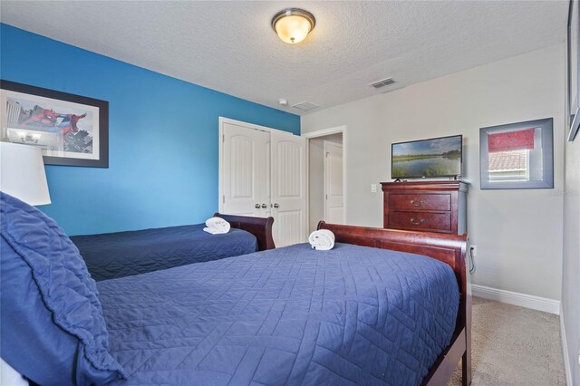 carpeted bedroom featuring a textured ceiling and a closet